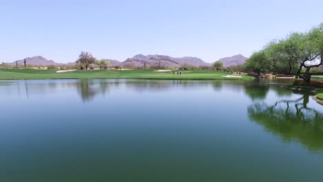 Varios-Golfistas-Caminan-Hacia-El-Green-Frente-Al-Peligro-De-Agua-En-El-Campo-De-Golf-Greyhawk,-Scottsdale,-Arizona