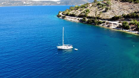 Sailboat-Sailing-On-The-Blue-Ocean-At-Agia-Sofia-Beach-In-Greece---aerial-shot