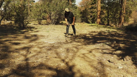 Man-walking-in-the-forest-gather-branches-from-the-ground-and-walking-out-of-frame