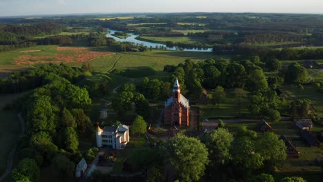 Red-Brick-Church-In-The-Small-Town-Kernave-In-Lithuania---aerial-drone-shot