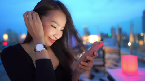 Close-up-of-happy-asian-female-scrolling-messages-on-her-smarphone