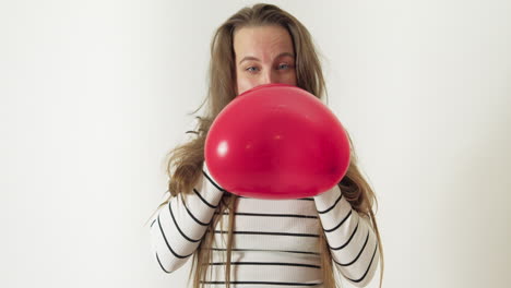 A-woman-with-long-hair-inflates-a-red-heart-shaped-balloon-with-her-mouth