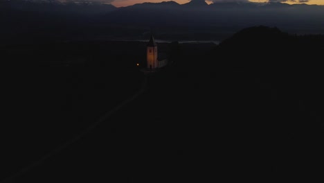 Early-morning-dark-scenery-at-St-Primoz-church,-aerial