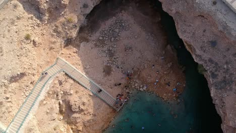 Spinning-drone-shot-of-Bimmah-Sinkhole-with-turquoise-water-near-Muscat-in-the-Sultanate-of-Oman