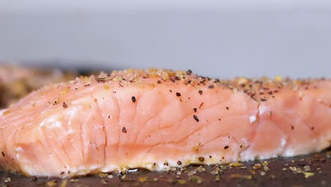 Uncooked-raw-single-salmon-sushi-being-cooked-with-spices-being-sprinkled-to-season-food,-close-up-static-side-view