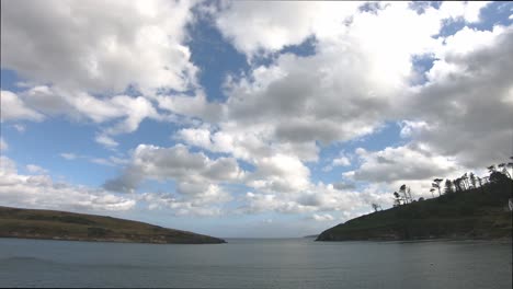 Time-lapse-passing-white-clouds-over-water-surface-and-blue-sky-with-land-on-both-sides
