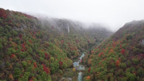 Plitvice-valley-during-colorful-fall-season-with-low-hanging-mist,-aerial