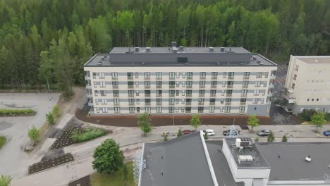 Aerial-shot-of-apartment-house-with-forest-in-the-background-in-summer