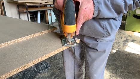Carpenter-cutting-off-a-corner-piece-of-a-wooden-plank-in-a-carpenter-workshop