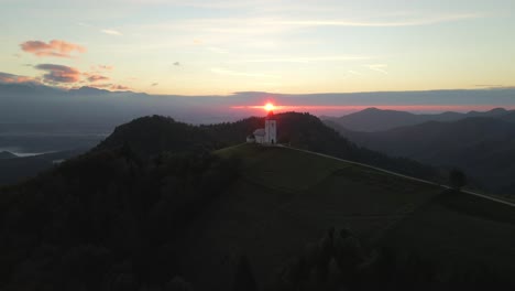 Mountain-church-in-Slovenia-during-morning-sunrise,-aerial