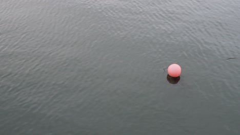 Faded-solo-red-sea-buoy-floating-on-blue-green-water
