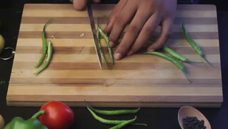 cutting-green-chili-on-a-wooden-chopping-board-by-the-chef-in-a-kitchen