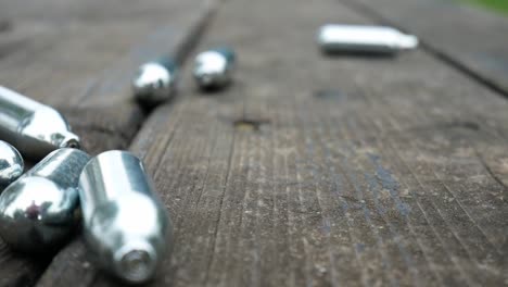 Multiple-dropping-chrome-nitrous-oxide-laughing-gas-drug-cylinders-on-wooden-bench