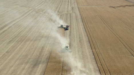 Aerial-view,-combine-harvesters-working-on-a-farm-field,-collecting-wheat-grains