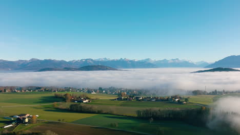 Savigny-Village-Appearing-From-Winter-Fog-Covering-The-Geneva-Lake-Region-With-The-Alps-In-The-Background-In-Vaud,-Switzerland