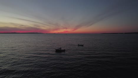 Twilight-scenery-of-two-local-fishing-boats-floating-on-calm-sea,-nightfall,-aerial