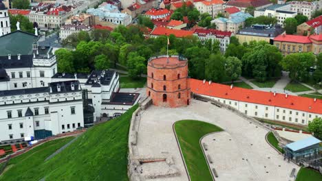 Fliegen-Sie-über-Den-Gediminas-Schlossturm-Mit-Wehender-Flagge-In-Vilnius,-Litauen