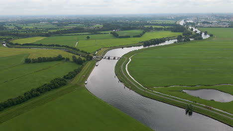 High-aerial-of-rustic,-rural-landscape-with-river-and-green-field-in-Holland
