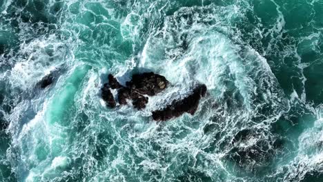 Aerial-shot-of-blue-waves-crashing-on-rocks-in-Pacific-Ocean,-Big-Sur-California