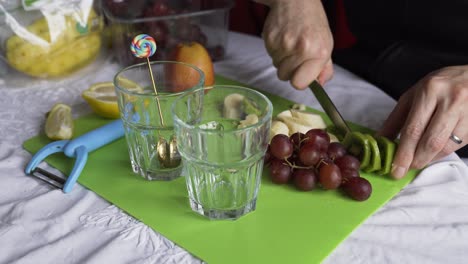 Cutting-kiwi-with-grapes-and-banana-for-a-fresh-fruity-breakfast