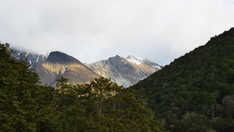 Pan-Shot-Forested-Mountains-with-Snow-Capped-Peaks-in-Background