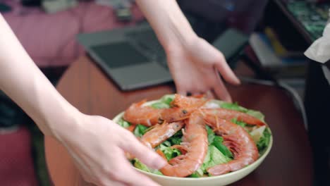 Seafood-Salad-Being-Served-On-The-Wooden-Table-With-Laptop-On-The-Side