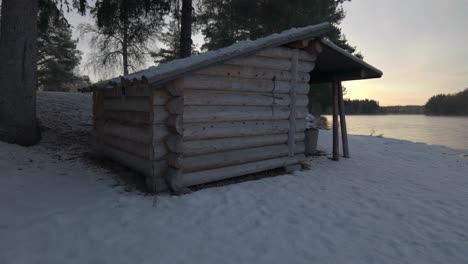 Wooden-Shelter-Next-To-River,-Snow-Landscape,-Pan