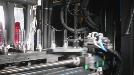 A-closeup-look-at-the-piece-of-robotized-equipment-producing-plastic-bottles-from-transparent-PET-plastic-preforms