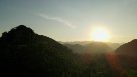 Aerial-footage-sliding-to-the-right-revealing-a-silhouette-created-by-the-sun-setting-of-mountains-and-hills-of-Khao-Yai-National-Park,-Thailand