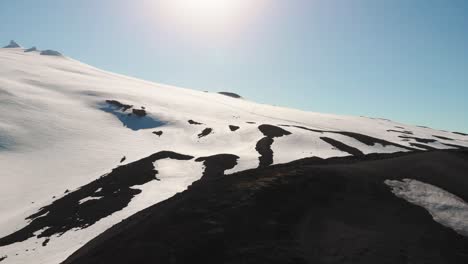 Beautiful-drone-flight-over-contrasty-white-snow-and-black-soil-of-Snaefellsjokull-Glacier-in-Iceland-during-summer