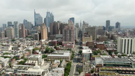 Aerial-pullback-shot-reveals-Philadelphia-skyline,-looking-north-on-Broad-Street-toward-City-Hall-on-cloudy-summer-day