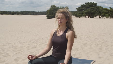 Statische-Aufnahme-Einer-Schönen-Frau,-Die-In-Sanddünen-Meditiert