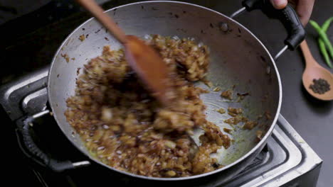 frying-finely-chopped-onion-in-a-deep-cooking-pan,-adding-ginger-garlic-paste