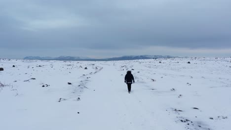 Aventurero-Solitario-Caminando-En-Un-Vasto-Campo-Abierto-Cubierto-De-Nieve-Blanca-En-Islandia