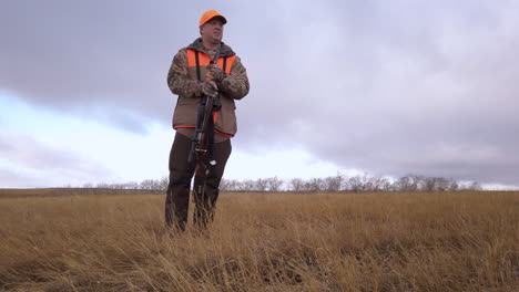 Ein-Männlicher-Jäger-Mit-Seinem-Hund,-Der-Sich-Auf-Die-Jagd-Auf-Einer-Ländlichen-Farm-In-Saskatchewan,-Kanada,-Vorbereitet---Ganzkörperaufnahme