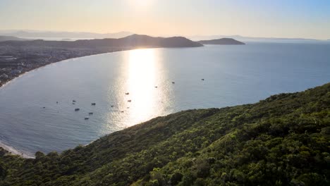 Sunset-drone-scene-seen-from-above-with-paradisiacal-beach-and-mountains-in-florianopolis-fishing-boats-in-the-late-afternoon-Ingleses-beach