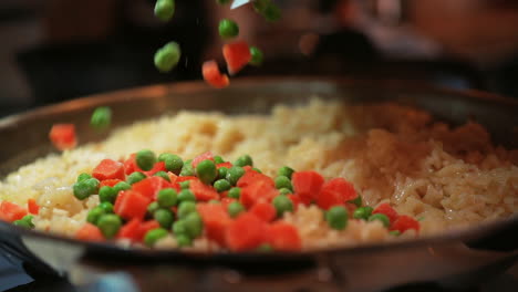 Adding-peas-and-diced-carrots-to-the-savory-rice-dish---isolated-slow-motion