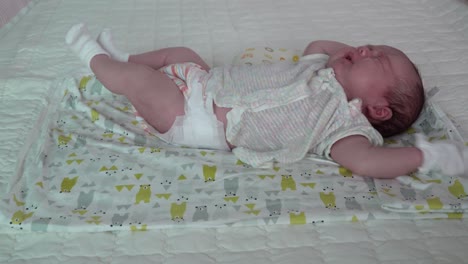 An-Adorable-Newborn-Baby-Lying-In-The-Bed-Stretches-And-Starts-To-Cry---close-up