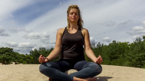 Time-lapse-of-Woman-meditating-in-sand-dunes---zoom-in