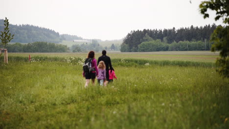 Static-FHD-shot-of-a-family-with-two-little-daughters-hiking-through-a-picturesque-countryside-of-Dolní-Morava,-Czech-Republic,-with-fields-and-forests-all-around