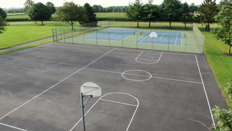 Aerial-reveal-of-basketball-court-and-tennis-courts-at-school-playground,-athletics-and-sports-theme-in-rural-America