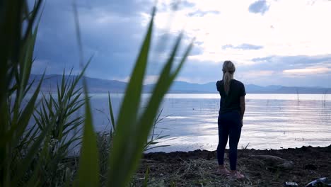 Utah-Lake,-young-woman-standing-on-the-shore-watching-the-sunset