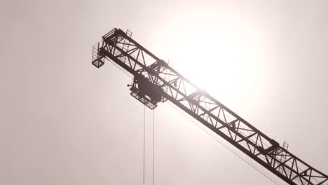 Construction-tower-crane-jib-and-trolley,-bright-sun-in-background