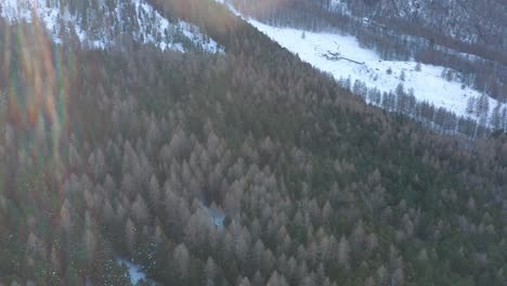 drone-flying-above-the-mountains-during-winter,-lateral-movement-tilting-up