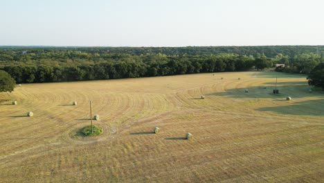 Long,-wide-aerial-orbit-shot-of-large-hay-field-showing-completed-round-hay-bales-throughout-the-field