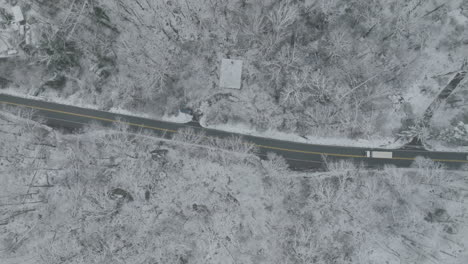 Top-down-aerial-video-of-trucks-and-cars-traveling-on-winter-road