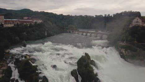 drone-shot-fly-straight-up-with-camera-tilting-down-at-large-waterfall-Rheinfall-in-Switzerland-in-4k