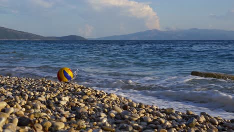 Ball-playing-on-sea-waves-splashing-on-tranquil-beach-with-pebbles-on-beautiful-coastline-of-Ion