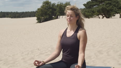 Neigung-Einer-Schönen-Frau,-Die-In-Sanddünen-Meditiert