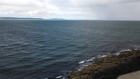 Luftaufnahme-Von-Wellen,-Die-An-Einem-Windigen-Tag-In-Bangor,-Nordirland,-Gegen-Die-Felsige-Küste-Schlagen